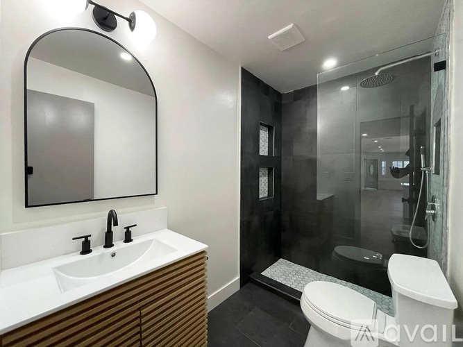 A modern bathroom with a white sink and a large mirror.