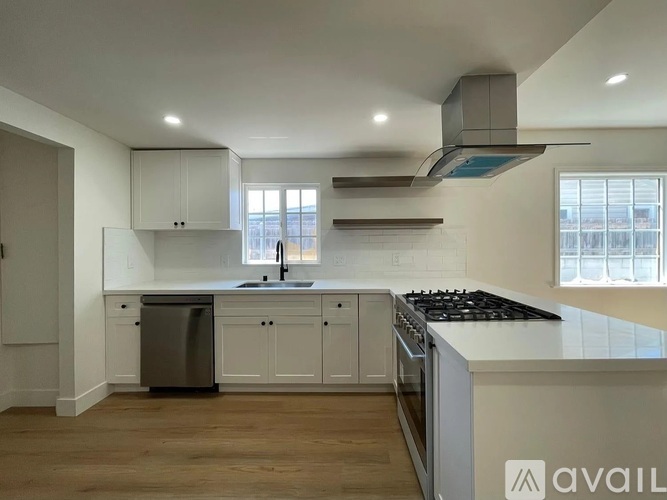 A modern kitchen with white cabinets and a black stove top.
