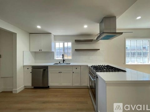 A modern kitchen with white cabinets and a black stove top.