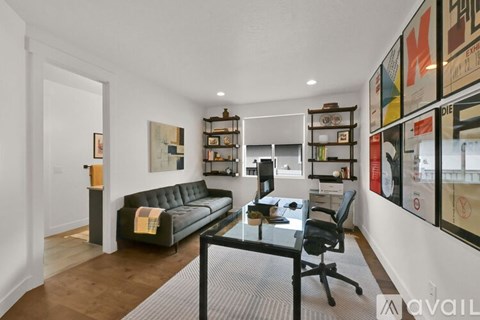 A modern living room with a black couch and a glass table.