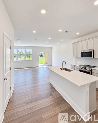 A modern kitchen with white countertops and wooden flooring.
