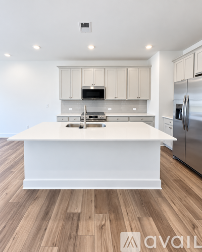 A kitchen with a white island and stainless steel appliances.