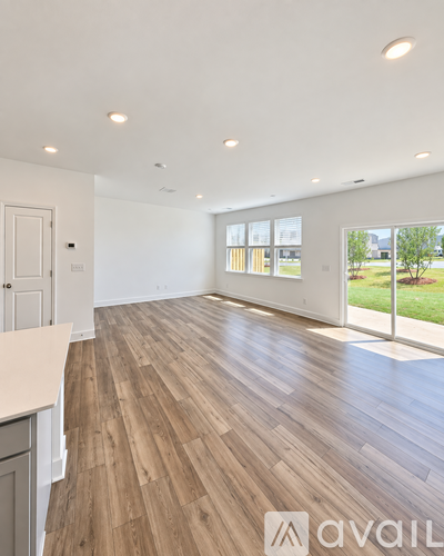 A spacious room with wooden flooring and a large window.