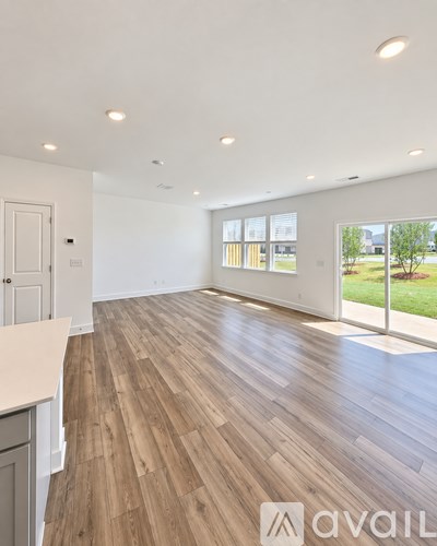 A spacious room with wooden flooring and a large window.