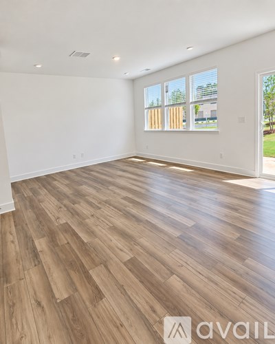 A spacious room with wooden flooring and large windows.