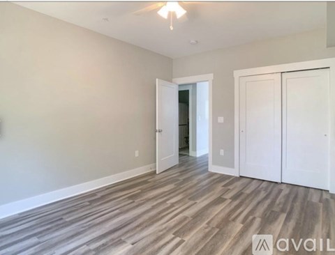 A room with wooden flooring and white walls, with two doors and a window.