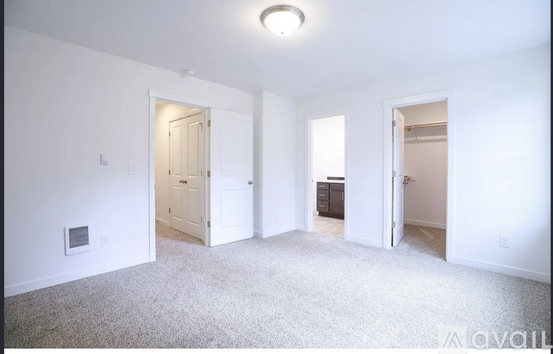 A white room with a carpeted floor and three open doors.