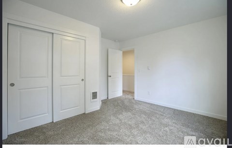 A carpeted room with two doors and a small window.