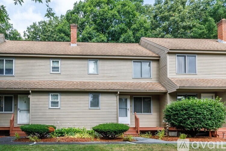 A two-story house with a front yard and a tree.