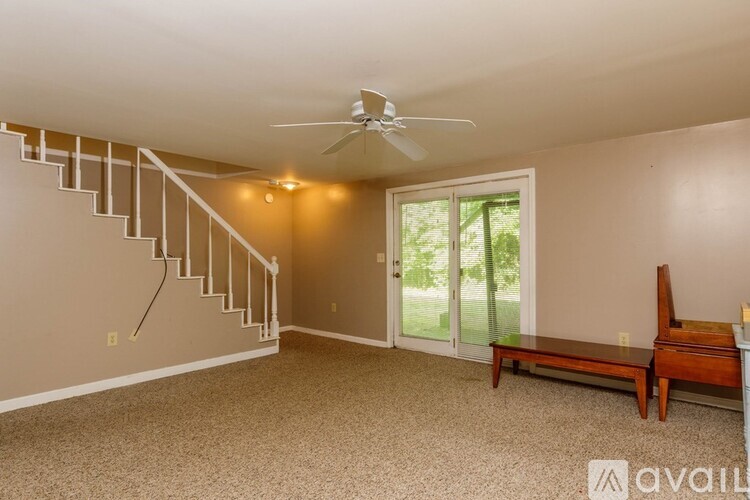 A living room with a staircase and a ceiling fan.