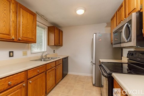 A kitchen with wooden cabinets and a black fridge.