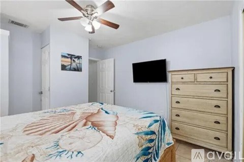 A bedroom with a bed, dresser, and a ceiling fan.