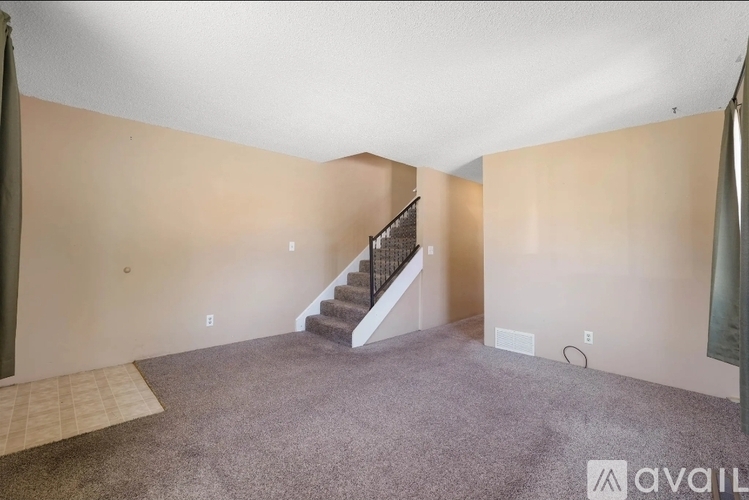 A spacious room with a staircase leading to the upper level.