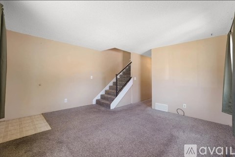 A spacious room with a staircase leading to the upper level.