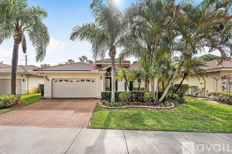 A house with a driveway and palm trees in front.