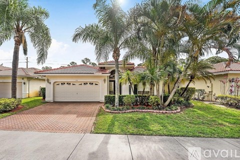 A house with a driveway and palm trees in front.