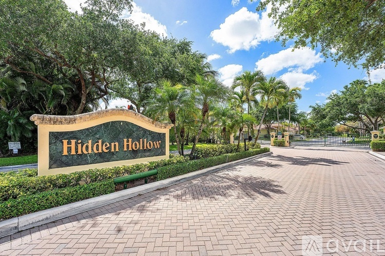A sign that says Hidden Hollow in front of a tree.