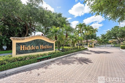 A sign that says Hidden Hollow in front of a tree.