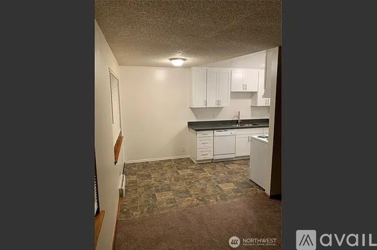 A kitchen with white cabinets and a brown floor.
