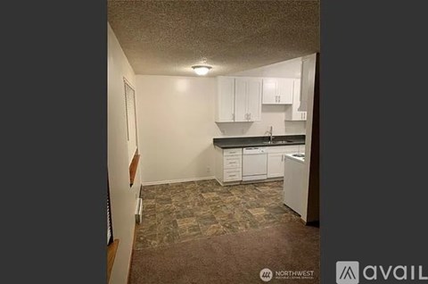 A kitchen with white cabinets and a brown floor.