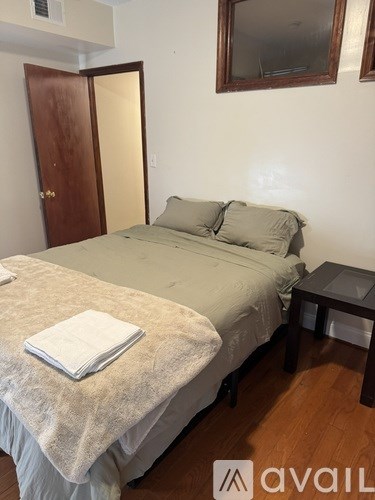 A bedroom with a bed, a small table, and a mirror on the wall.