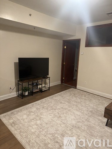 A living room with a flat screen TV and a rug on the floor.
