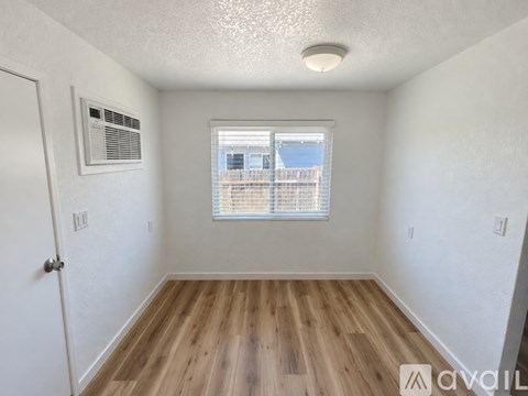 A room with wooden floors and a window with blinds.