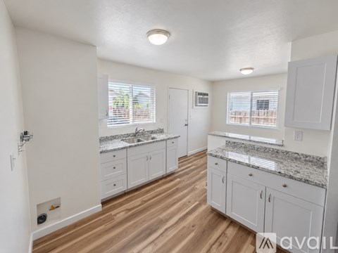 A kitchen with white cabinets and a granite countertop.