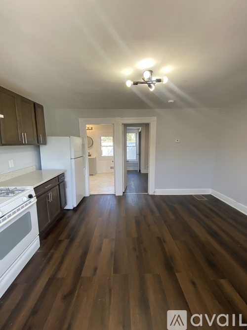 A kitchen with dark wood floors and white appliances.