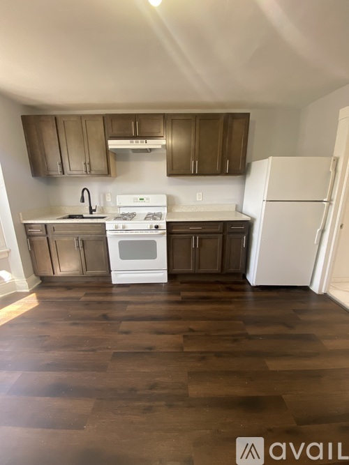 A kitchen with white appliances and wooden floors.