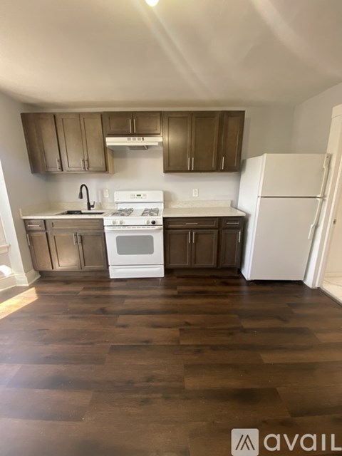 A kitchen with white appliances and wooden floors.