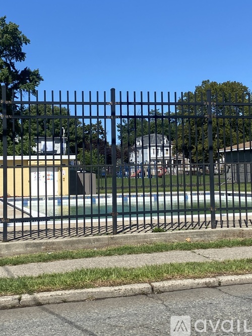 A black metal fence in front of a pool and a white house.