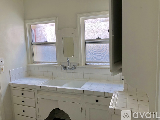 A bathroom with a white countertop and a window.