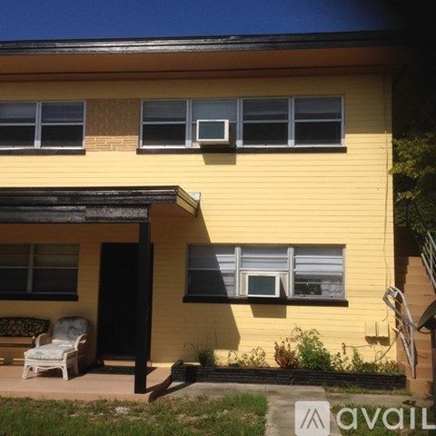 A yellow house with a porch and a white chair.
