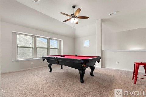 A room with a pool table and a ceiling fan.