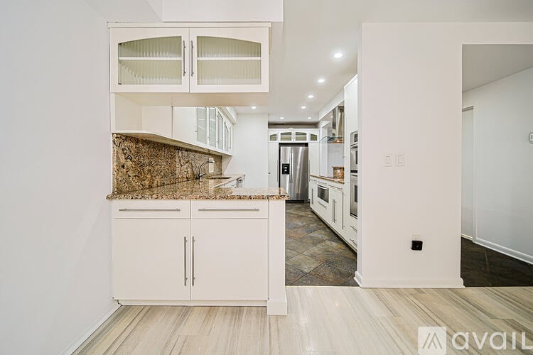 A kitchen with white cabinets and a granite countertop.