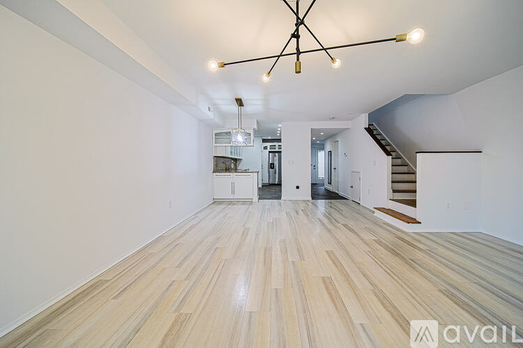 A spacious room with wooden flooring and a modern chandelier.