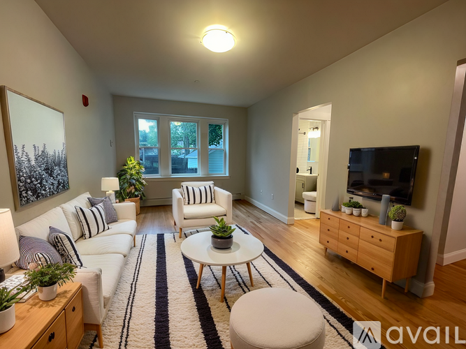 A living room with a white couch, a coffee table, and a television.