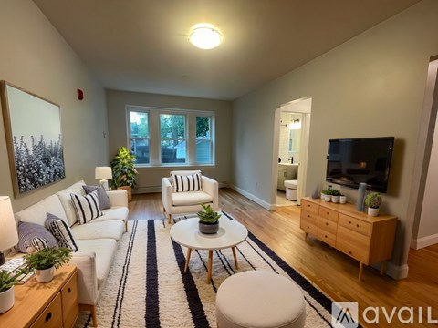 A living room with a white couch, a coffee table, and a television.