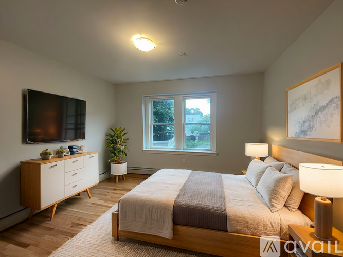 A well-lit bedroom with a large bed, a TV, and a window.