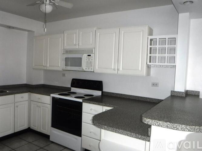 A kitchen with white cabinets and black countertops.