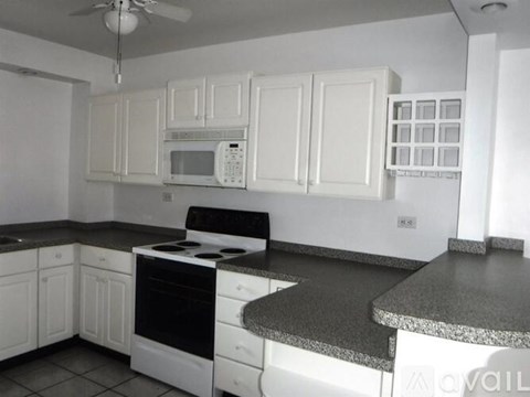 A kitchen with white cabinets and black countertops.