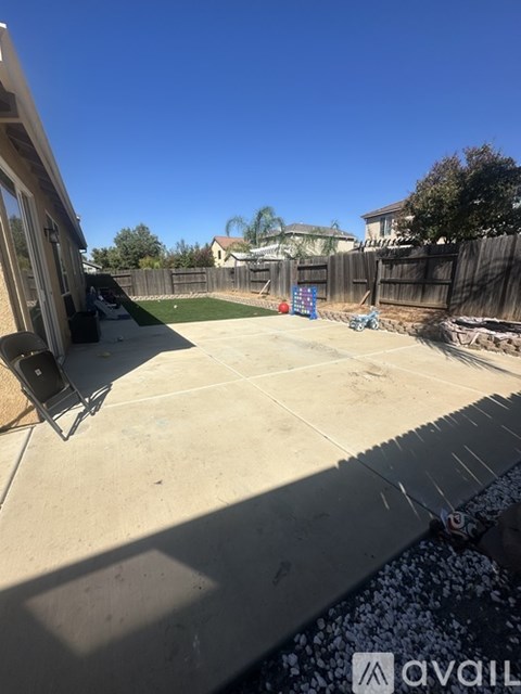 A backyard with a concrete patio and a fence.