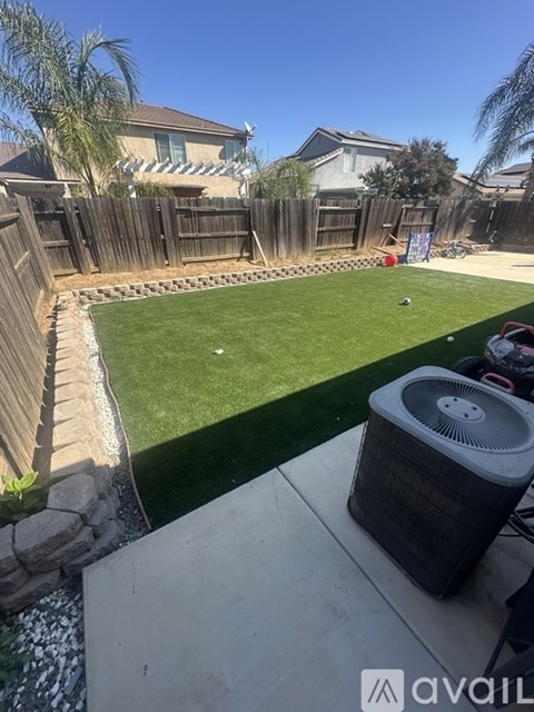 A backyard with a green lawn and a brown fence.