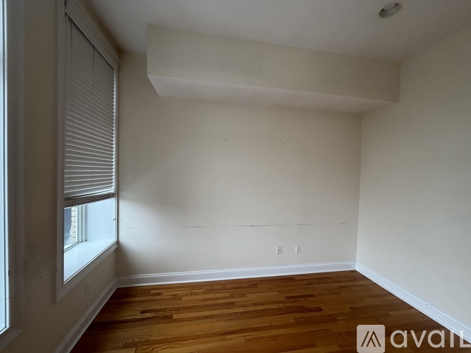 A room with wooden floors and white walls, with a window on the left side.