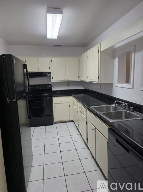 A kitchen with black appliances and white cabinets.