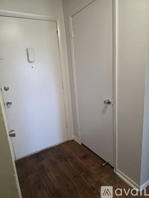 A white door with a silver handle and a white light switch on the wall.
