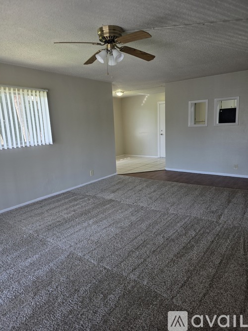 A room with a ceiling fan and carpeted floor.