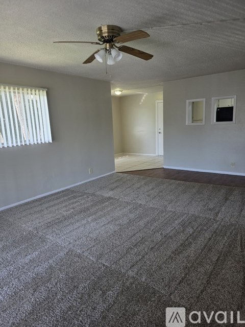 A room with a ceiling fan and carpeted floor.