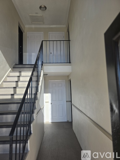A hallway with a staircase leading to a door.